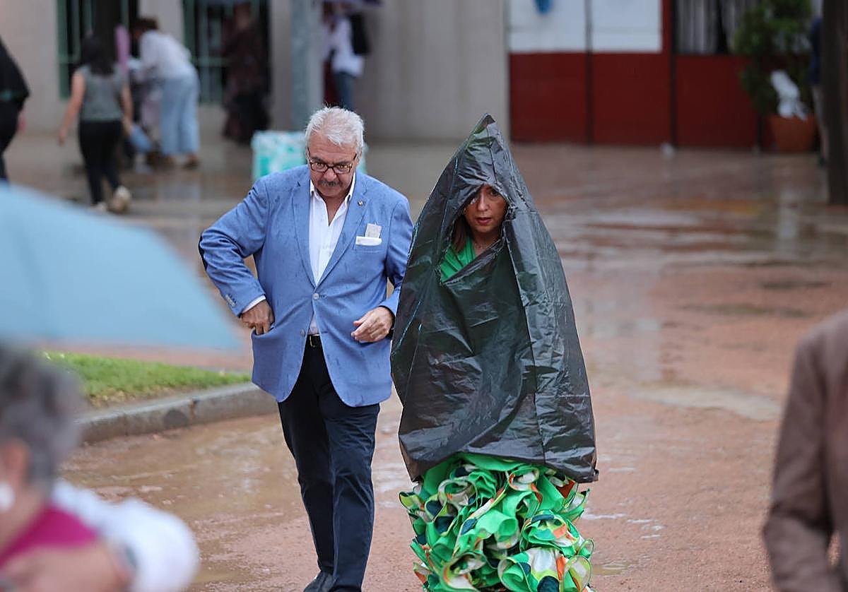 Una mujer vestida de flamenca se protege de la lluvia en la Feria de Córdoba