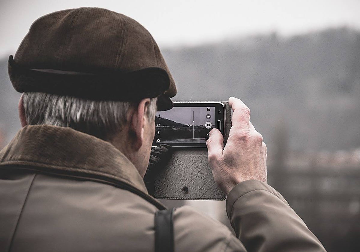 Un anciano utiliza un teléfono móvil para hacer fotografías
