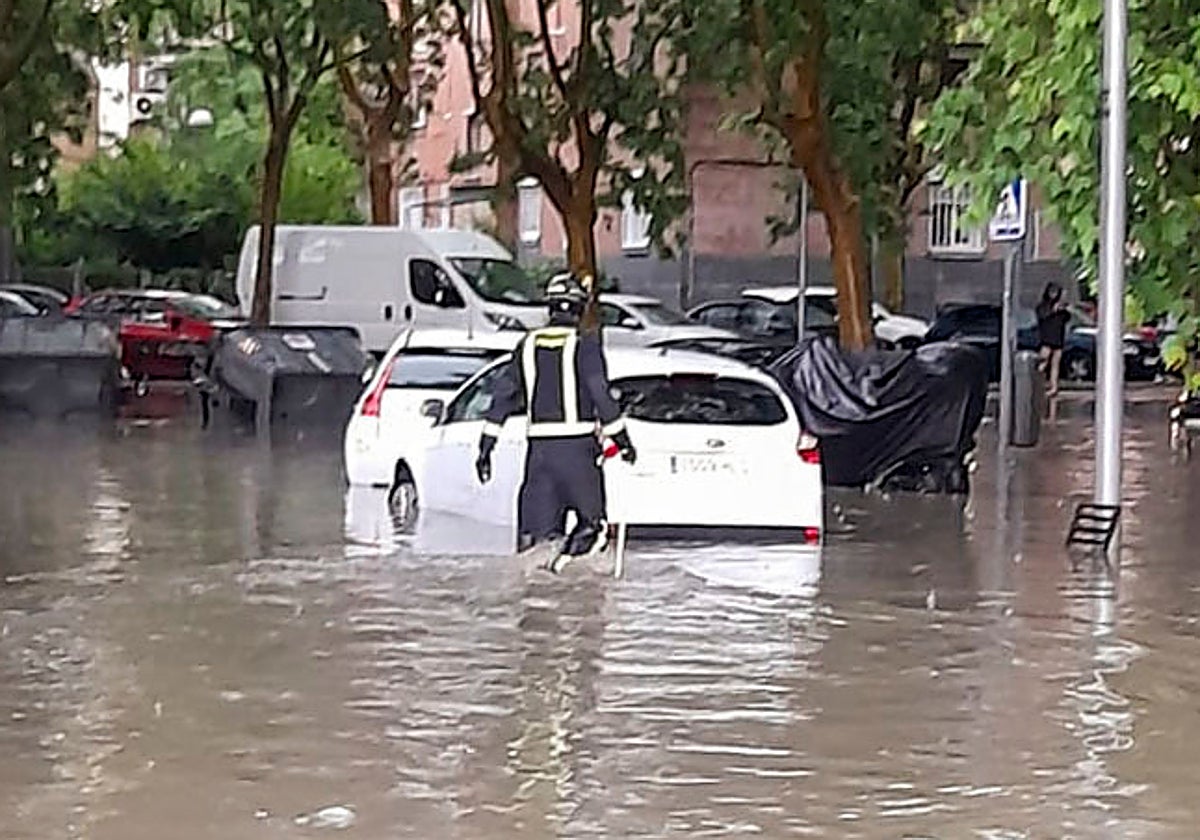 Un bombero en una zona de la capital con varios vehículos sobra una gran balsa de agua