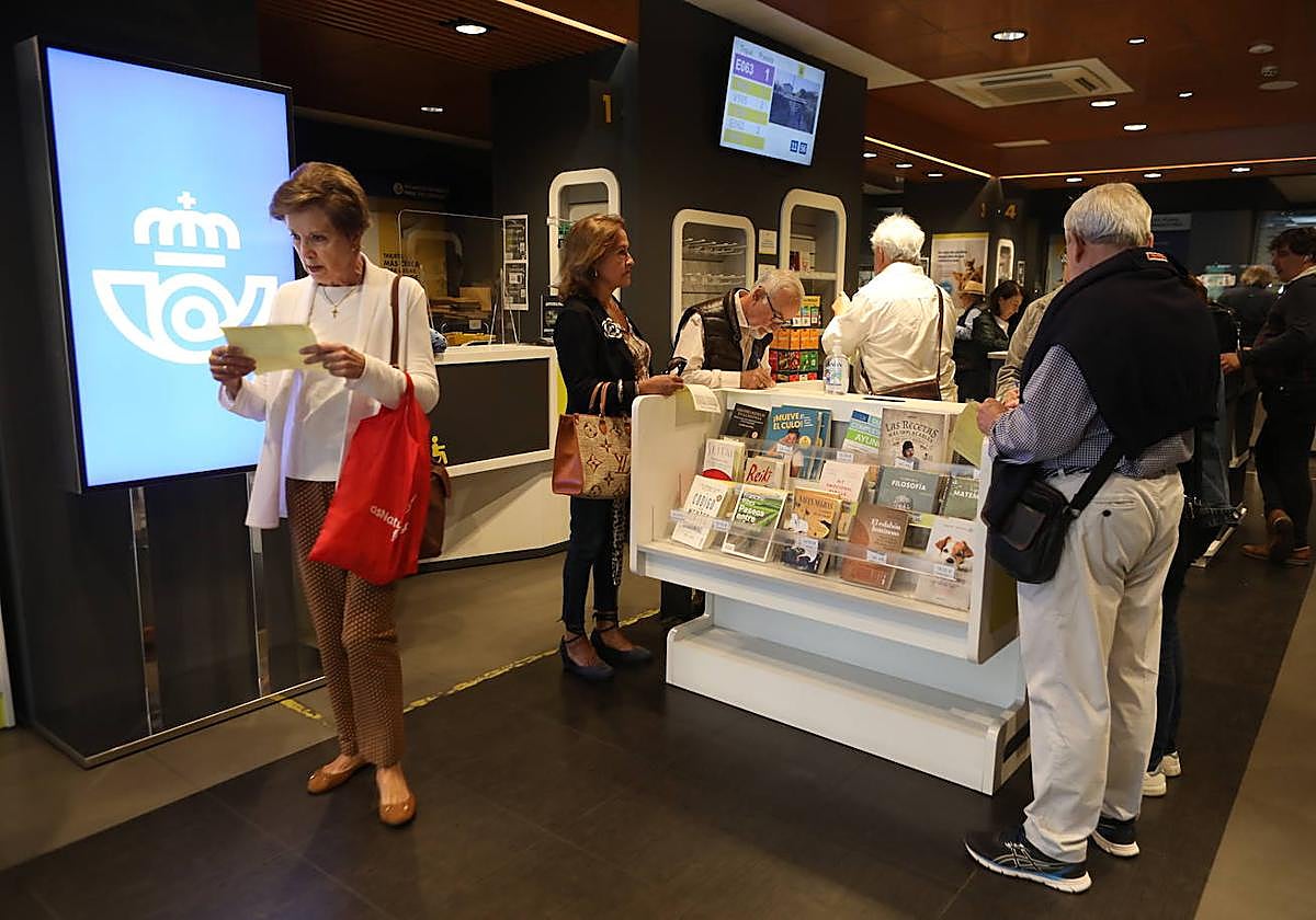 Varias personas rellenan la solicitud para pedir el voto por correo en una oficina de Correos