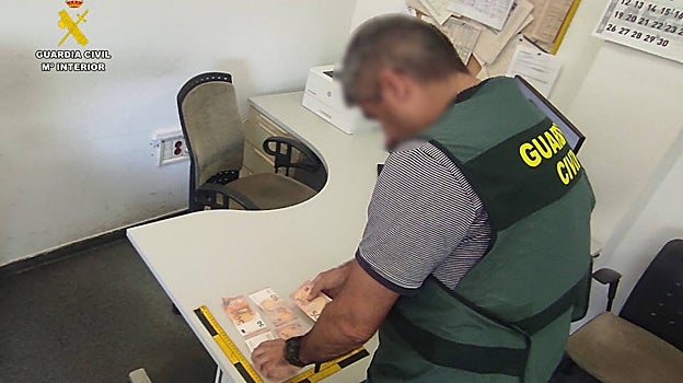Imagen de un guardia civil con los billetes falsos incautados