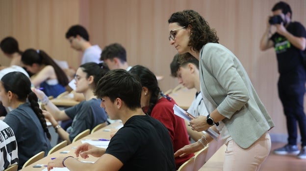 Un profesor atiende a un alumno que se examina de la Selectividad este 2023 en la facultad de medicina y enfermería de Córdoba