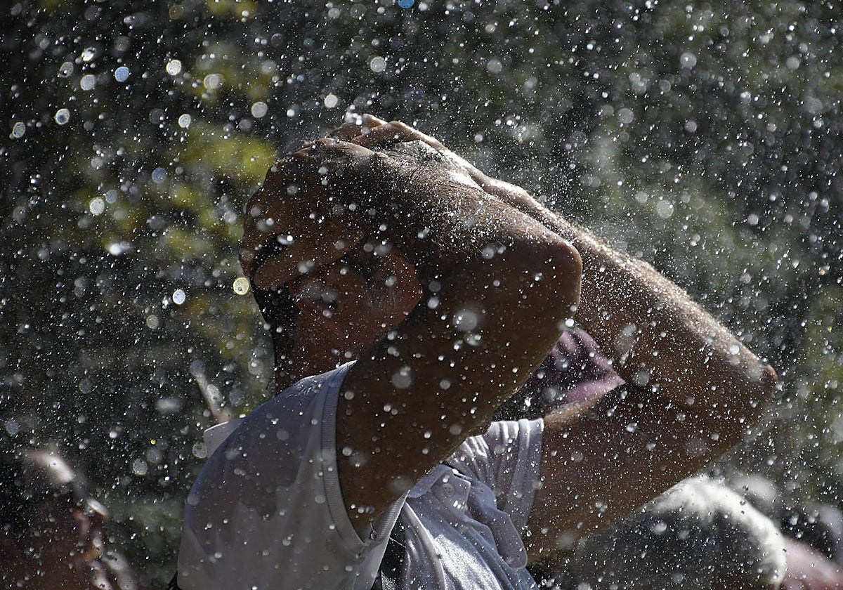 Un hombre se refresca en una fuente en una imagen de archivo