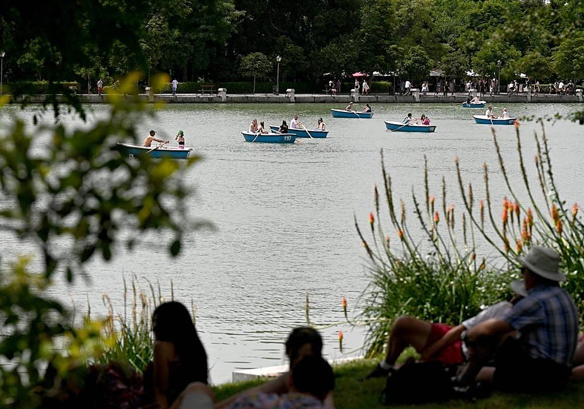 Varias personas se guarecen a la sombra en el parque de El Retiro