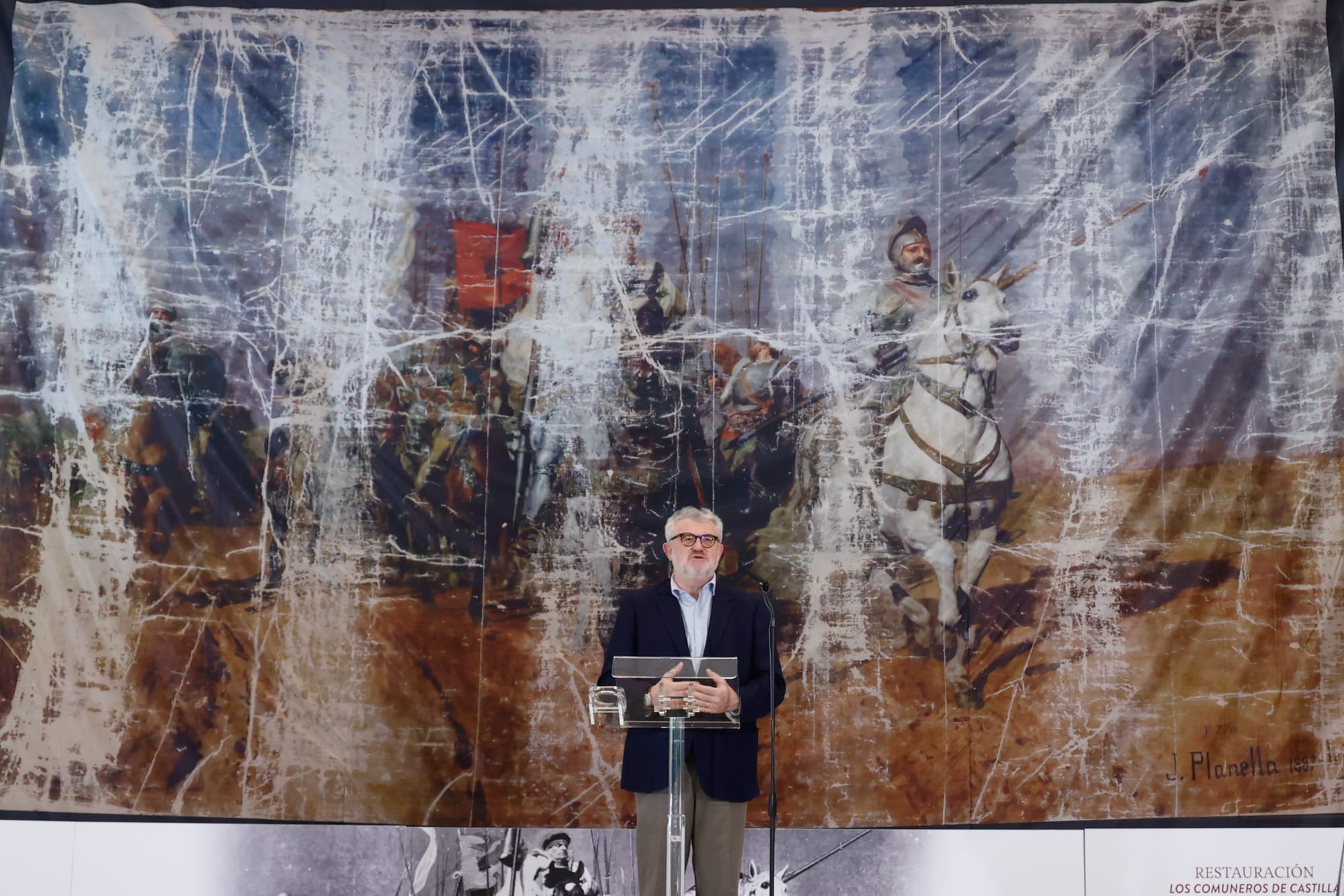 Miguel Falomir, director del Museo del Prado, interviene ante la lona que tapaba la restauración del cuadro y donde se puede ver el estado en el que llegó a las Cortes