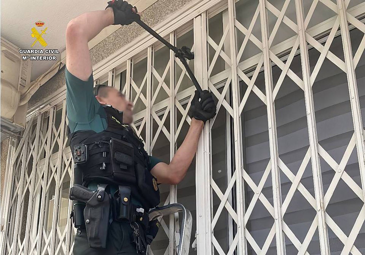 Imagen de un guardia civil forzando la reja de la vivienda para acceder y rescatar a la anciana