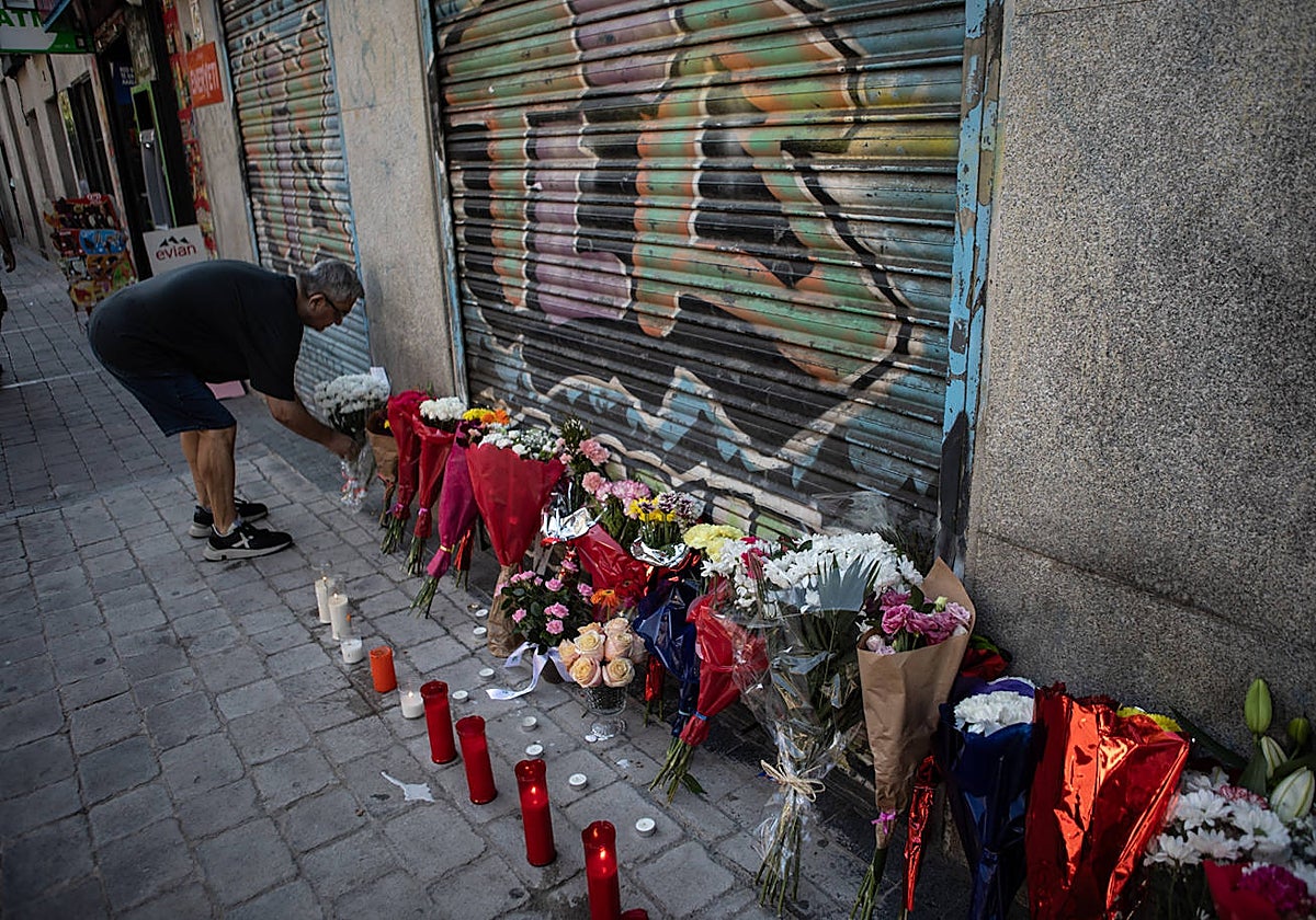 Un hombre coloca un ramo de flores en el altar dedicado a Concha en la entrada de su tienda en Tirso de Molina