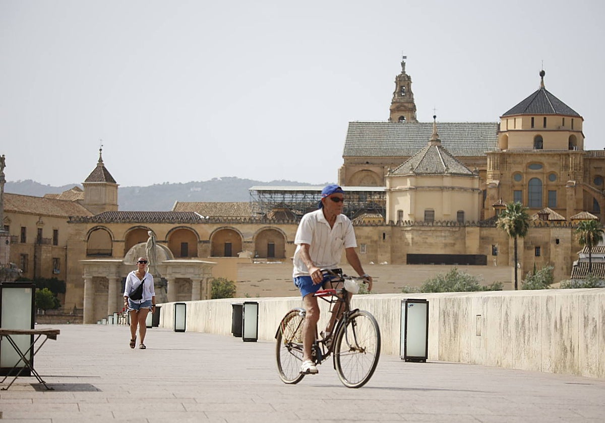 Dos personas pasan por el Puente Romano de Córdoba
