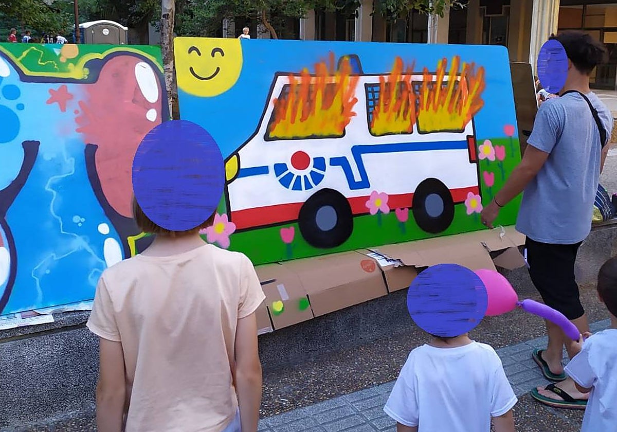 Varios niños y adultos observan el cartel retirado del concurso