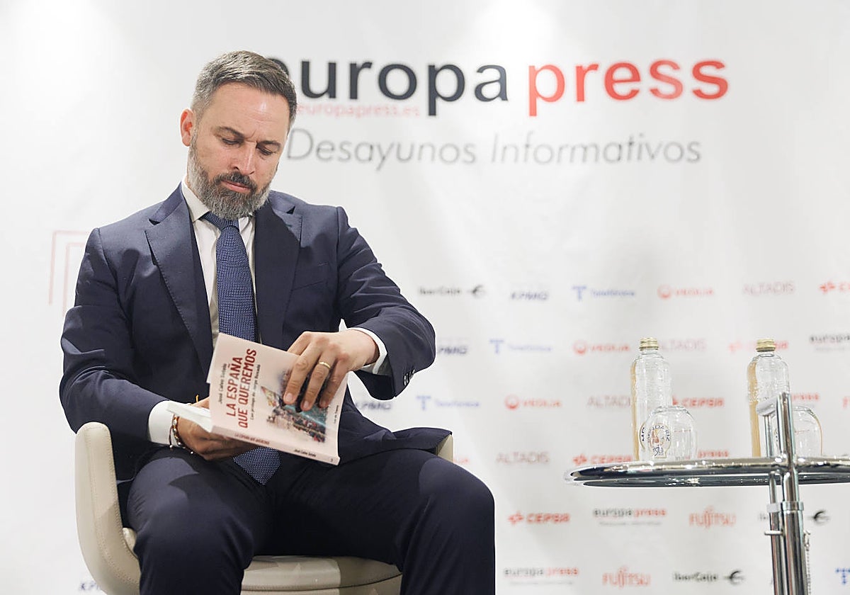 El presidente de Vox, Santiago Abascal, ojea el libro 'La España que queremos', en un desayuno informativo organizado por Europa Press