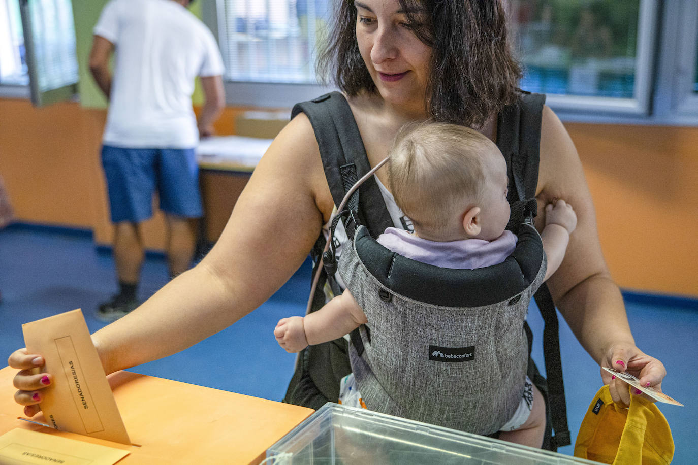 Una mujer deposita su voto mientras carga a su bebé