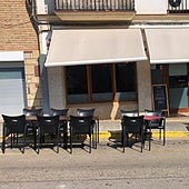 Un bar monta dos mesas de su terraza encima de un coche aparcado junto a la acera