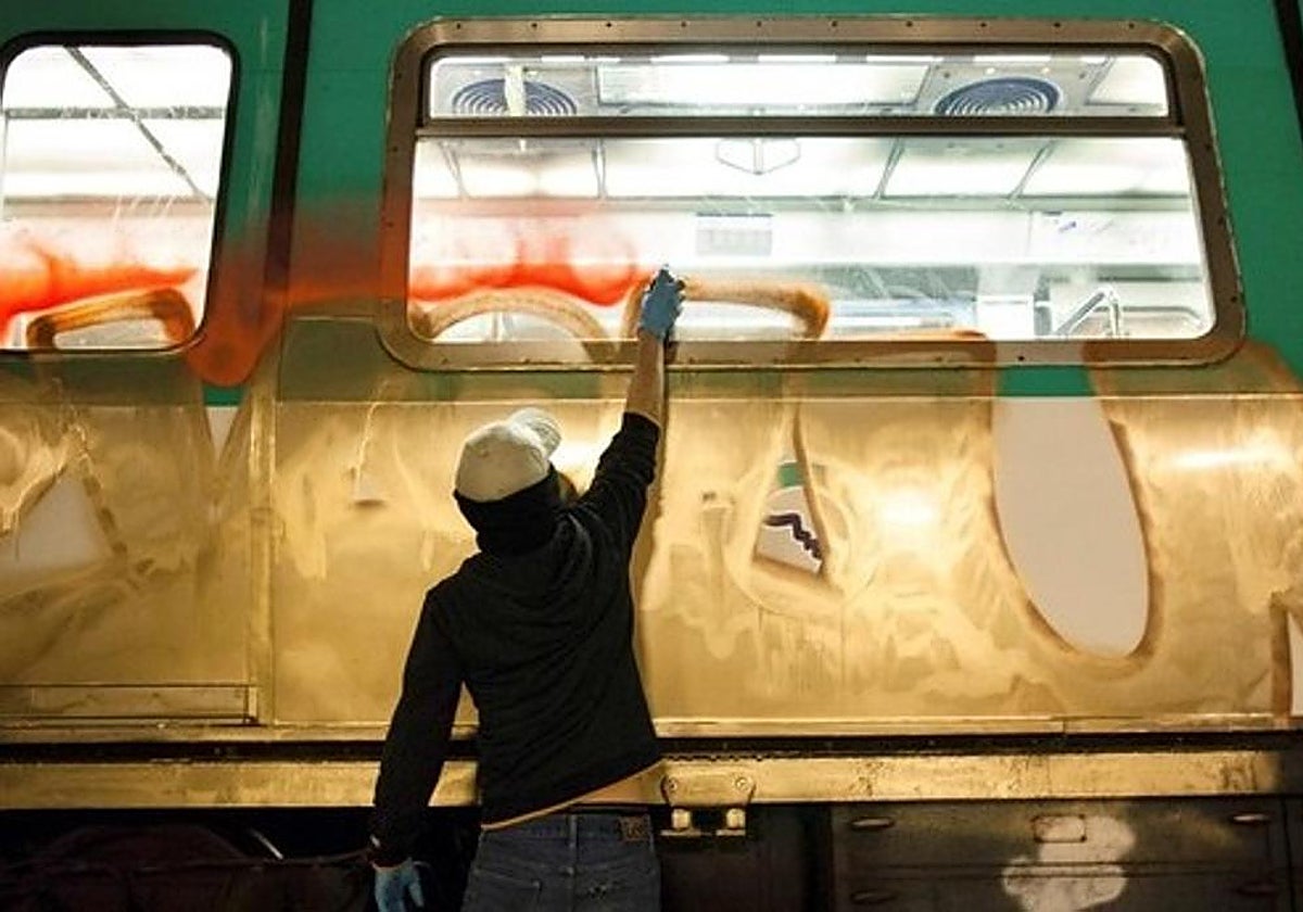 Un graffitero pinta en un vagón de tren