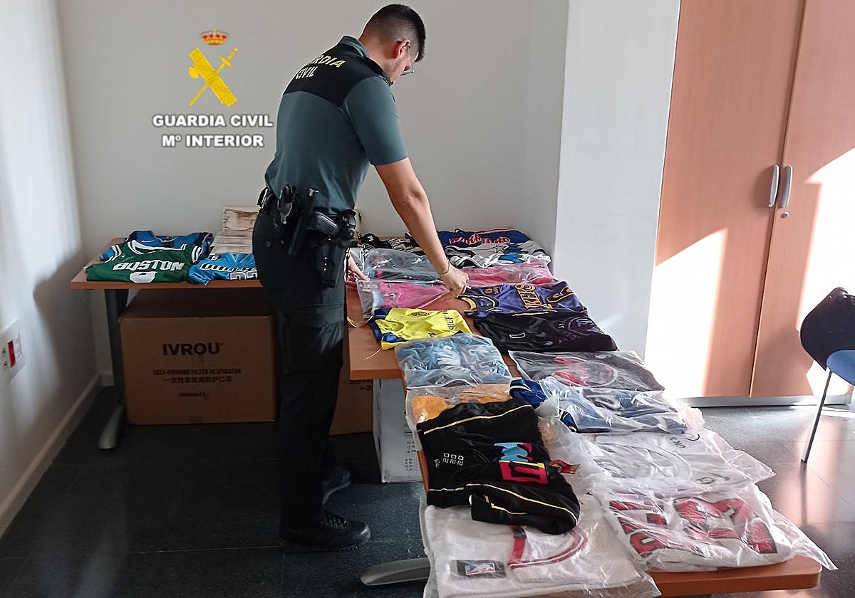 Imagen de un guardia civil clasificando las prendas falsificadas intervenidas en Castellón