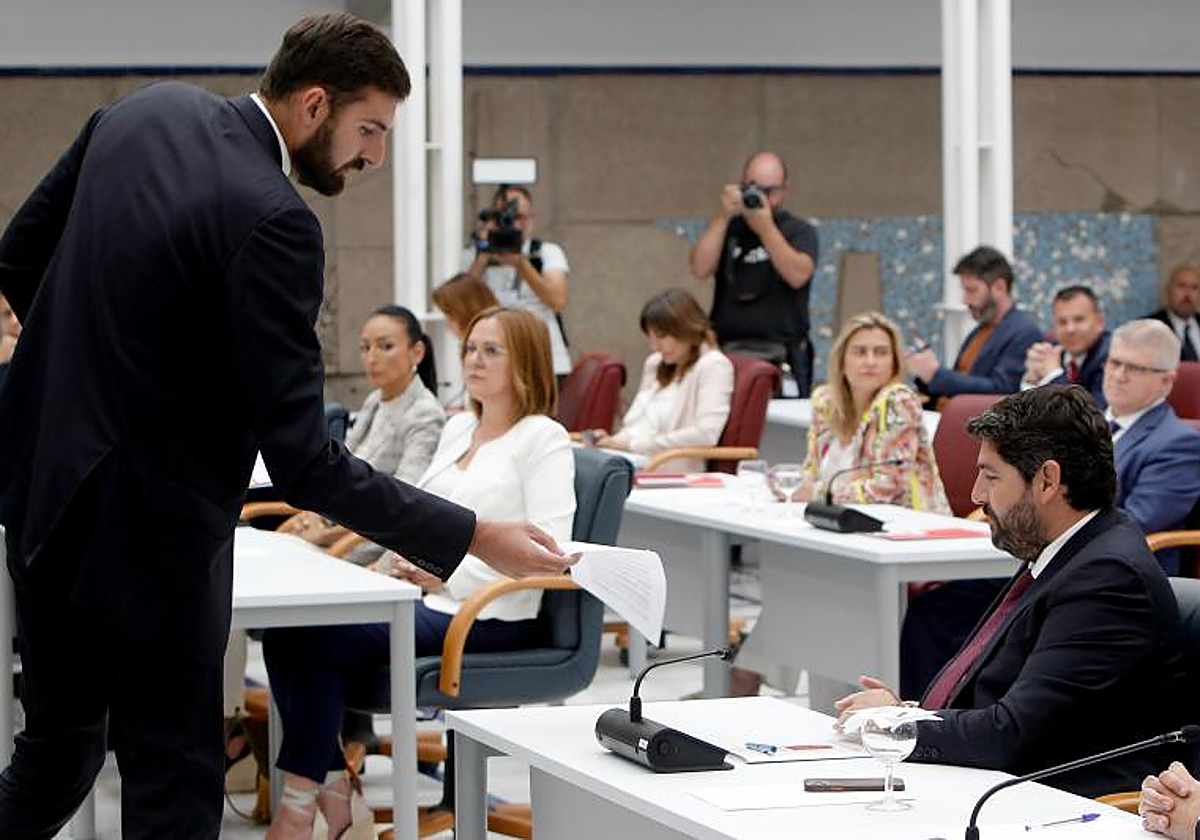 José Ángel Atelo, portavoz de Vox en la Región de Murcia, entrega un documento a Fernando López Miras, presidente autonómico e funciones y candidato del PP a repetir en el cargo regional, durante el debate de investidura fallido del segundo, el 10 de julio