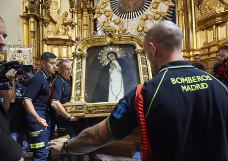 Imagen secundaria 1 - Los bomberos realizando el rito de bajar el cuadro de la Virgen