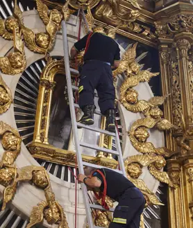 Imagen secundaria 2 - Los bomberos realizando el rito de bajar el cuadro de la Virgen