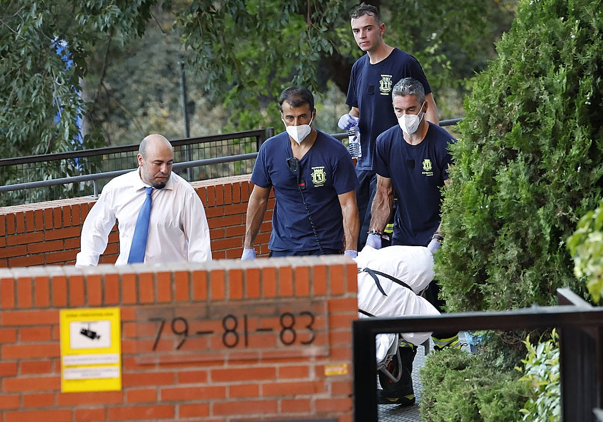 Los trabajadores de la funeraria sacan de la vivienda de Moratalaz uno de los cadáveres