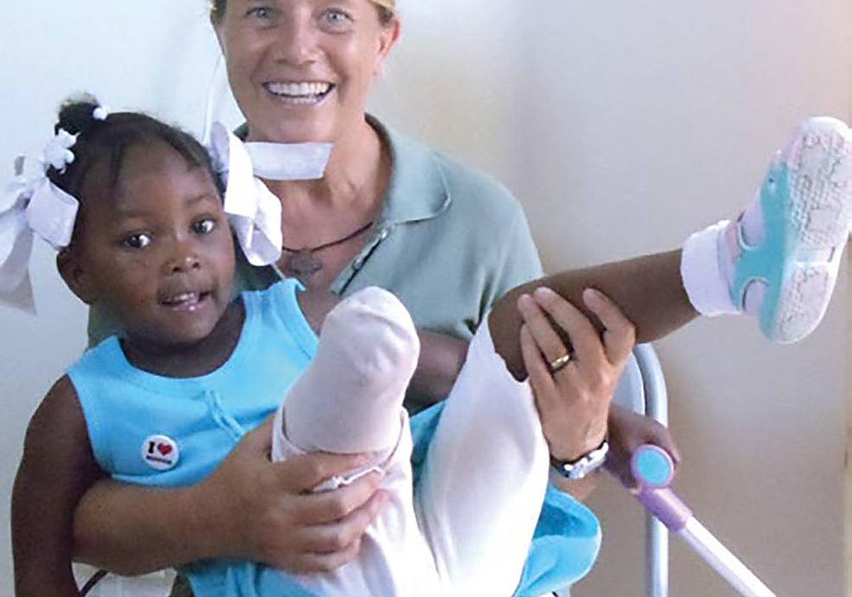 Imagen de una niña haitiana y una voluntaria de Manos Unidas