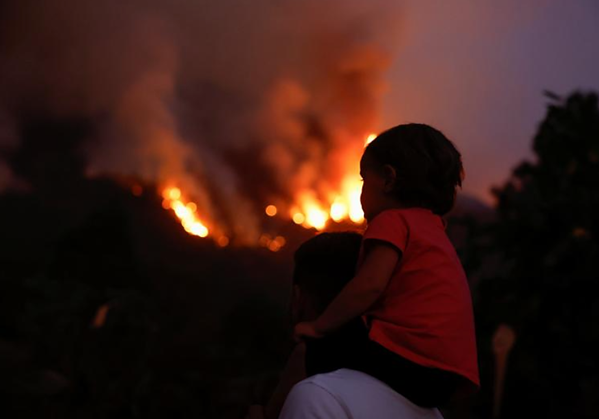 Un niño observa el incendio de Tenerife subido a hombros