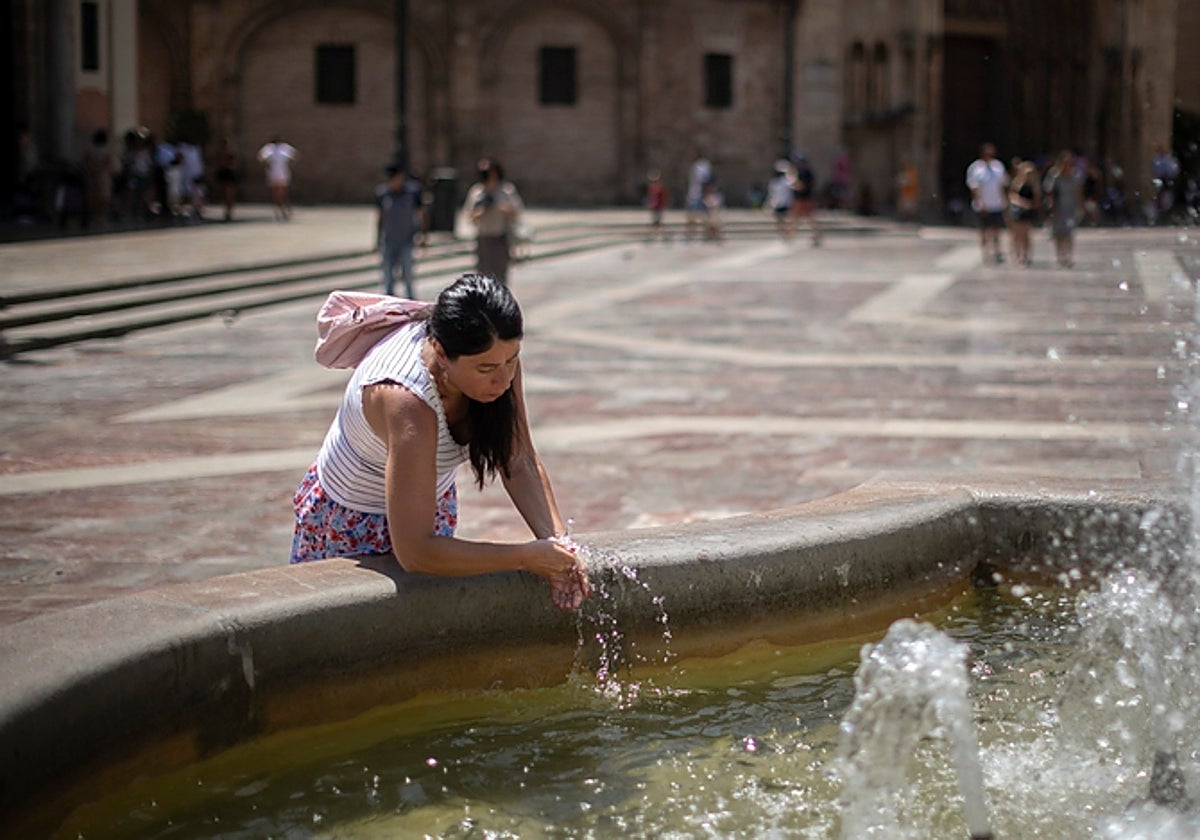 Imagen de una mujer refrescándose en una fuente del centro de Valencia