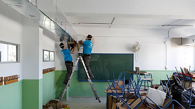 Dos operarios trabajan en el interior de un aula