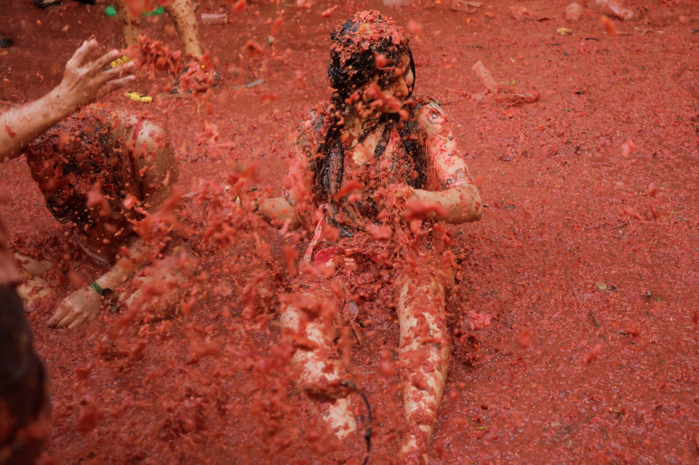 Una joven tirara en el suelo cubierto de tomate triturado en Buñol