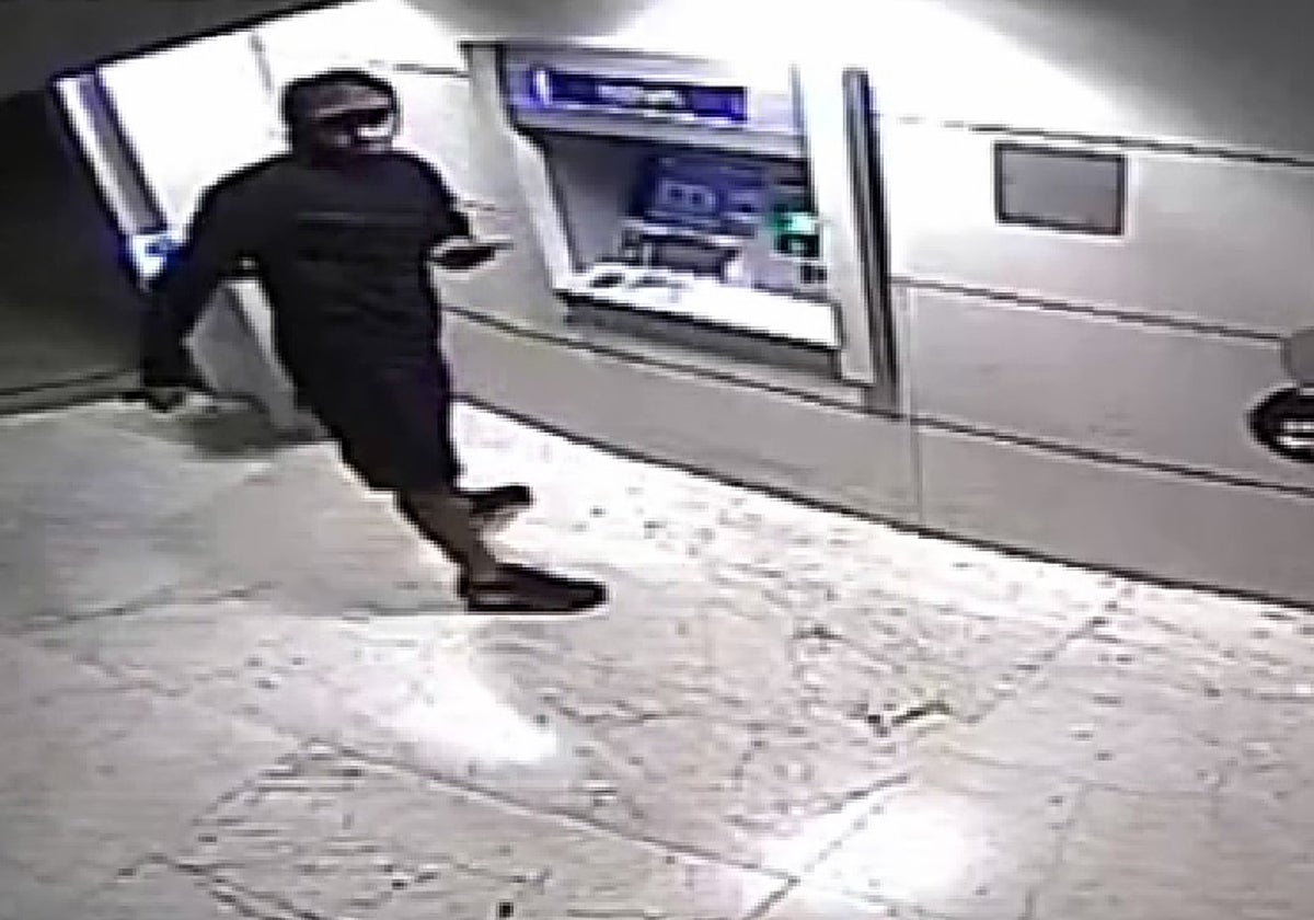 Uno de los ladrones saca dinero de un cajero automático