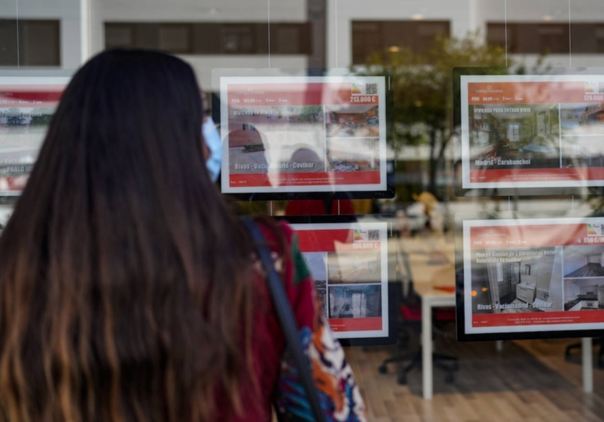 Una joven frente al escaparate de una inmobiliaria
