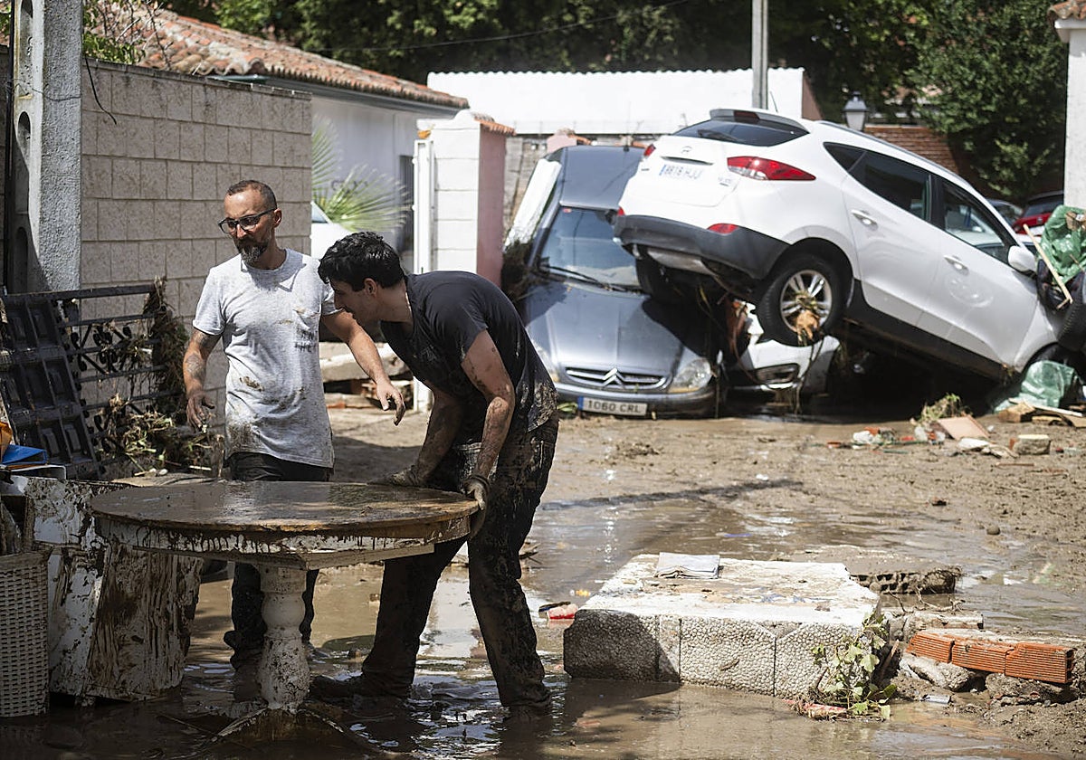 Dos vecinos de Villamanta salvan muebles; al fondo, coches apilados por el temporal