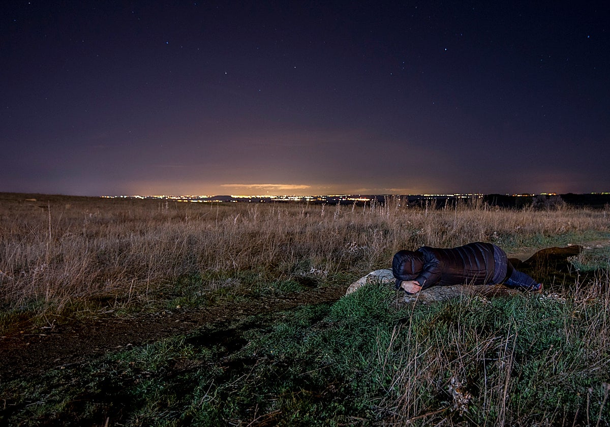Una persona tirada en una roca en medio del campo