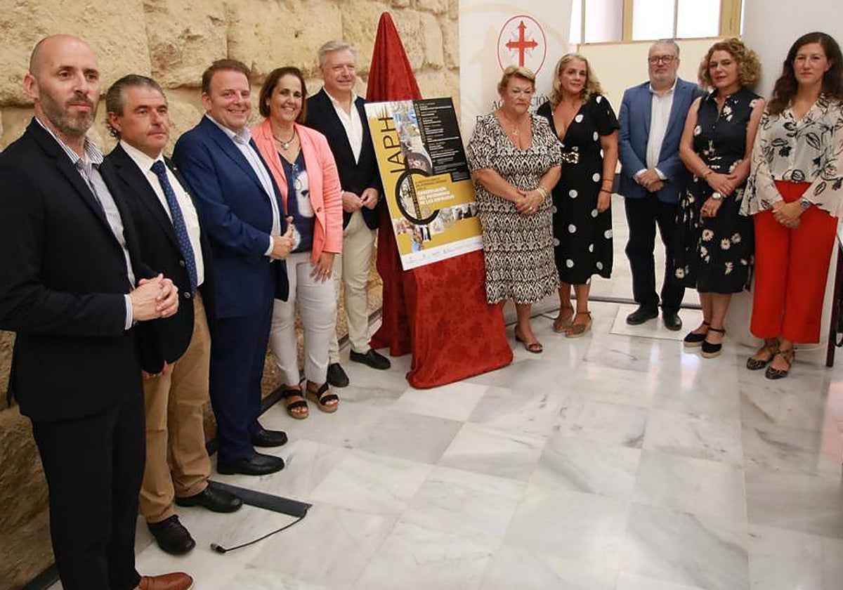 Blanca Torrent, Juan José Primo Jurado y Olga Caballero, en el centro junto al cartel, con otros representantes de la Junta de Andalucía, la Agrupación, el Ayuntamiento y Fundación Caja Rural del Sur, este lunes