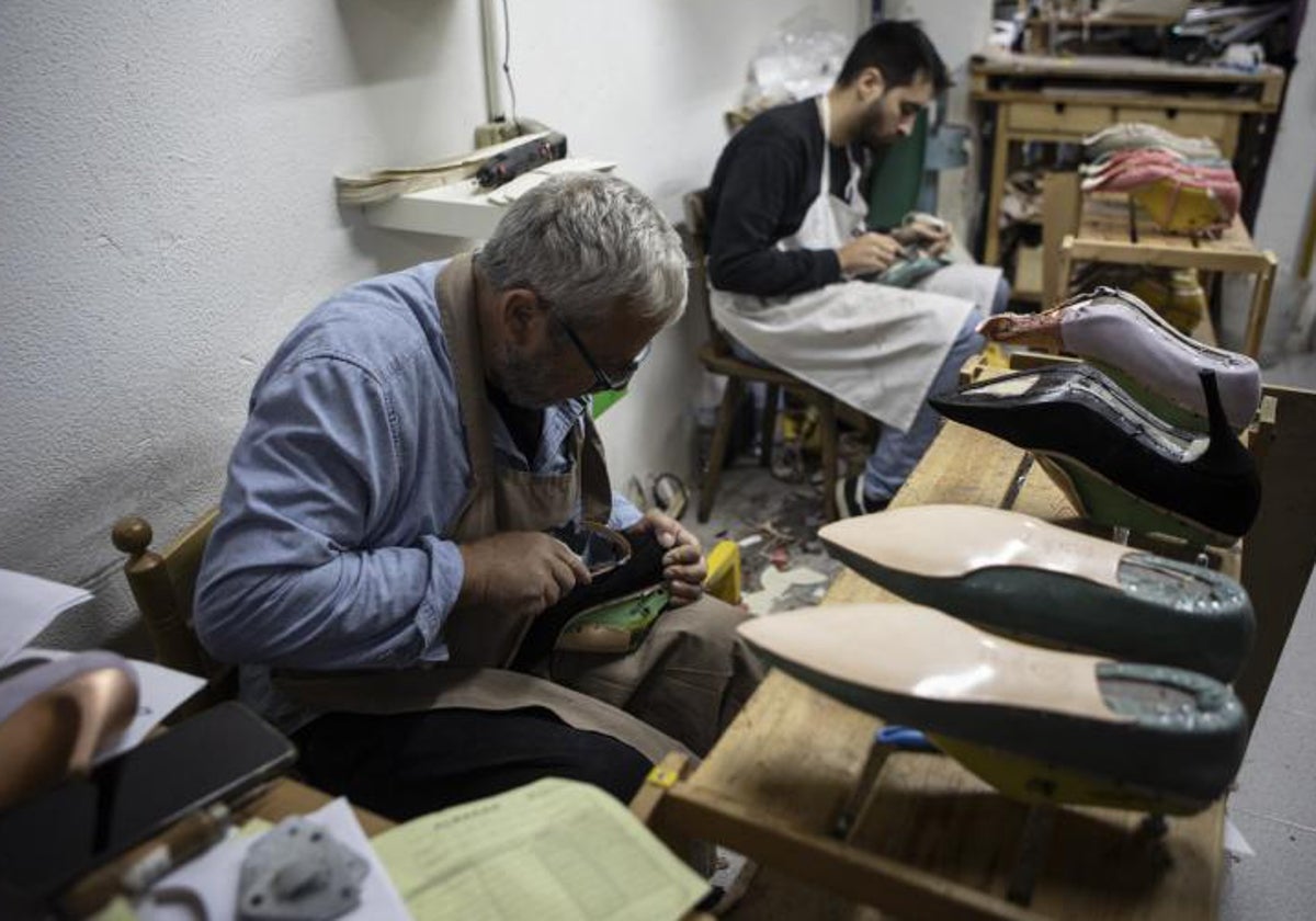 Dos artesanos trabajan con zapatos, a mano, en la capital