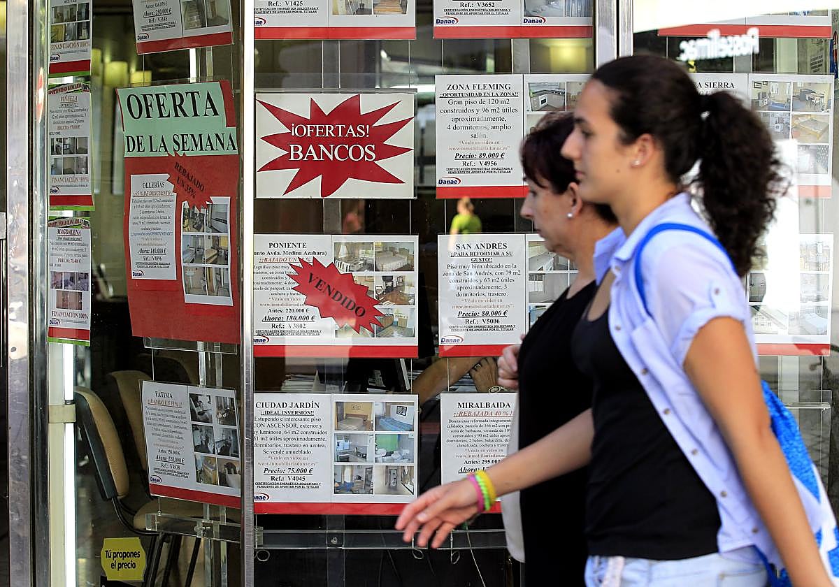 Dos mujeres pasan delante de la oficina de una inmobiliaria en Córdoba