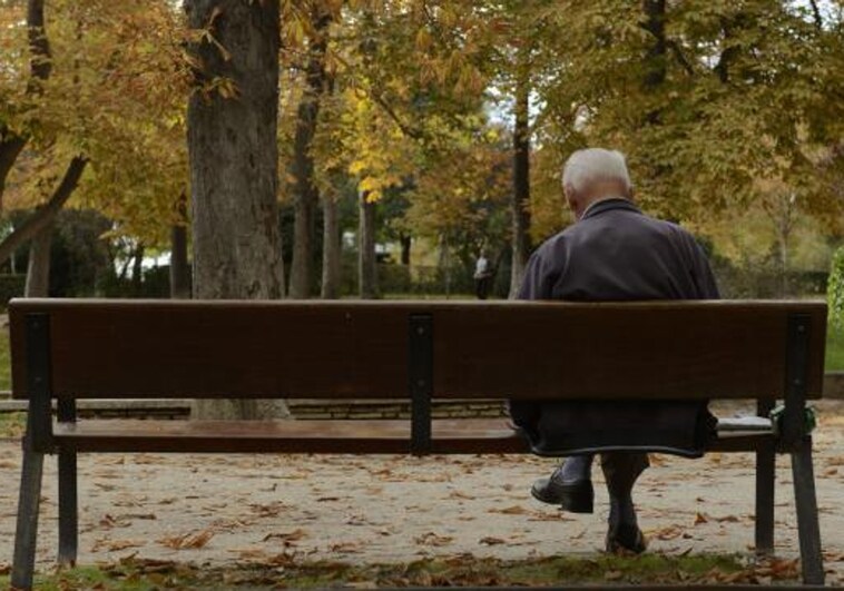 Un anciano sentado en un banco en El Retiro