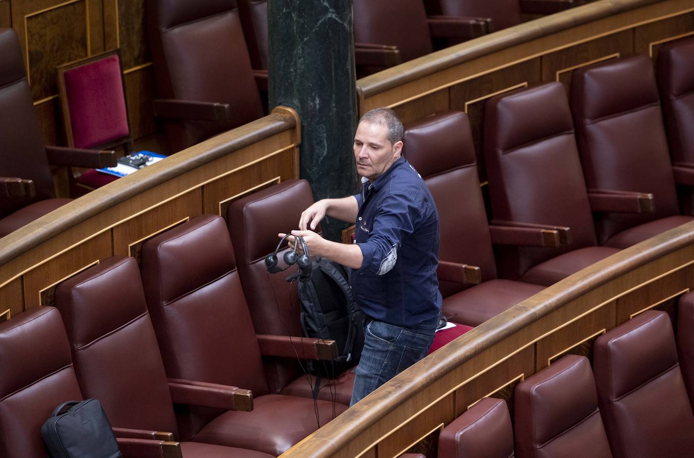 Un trabajador prepara los pinganillos para que los diputados puedan recibir la traducción simultánea de las lenguas cooficiales antes de la primera sesión del debate de investidura del líder del PP