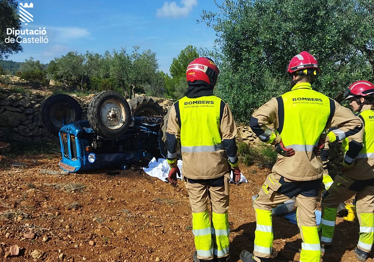 Efectivos de bomberos junto al tractor volcado en el lugar en el que ha muerto el conductor.