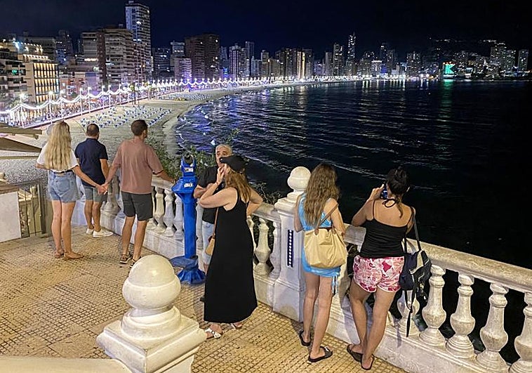 Turistas contemplan las vistas nocturnas de la Playa de Levante en Benidorm.