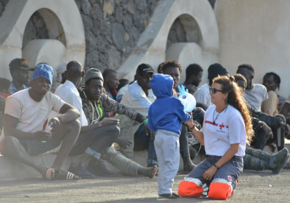 Una trabajadora de Cruz Roja juega con un niño pequeño llegado junto a 220 personas a La Restinga, El Hierro