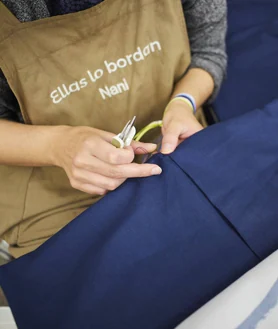 Imagen secundaria 2 - La responsable de producción del taller, Ángela Rossignoli (imagen principal), posa entre los productos de 'Ellas lo bordan'.  En las otras imágenes, detalles de los patrones y las manos de uno de los trabajadores.