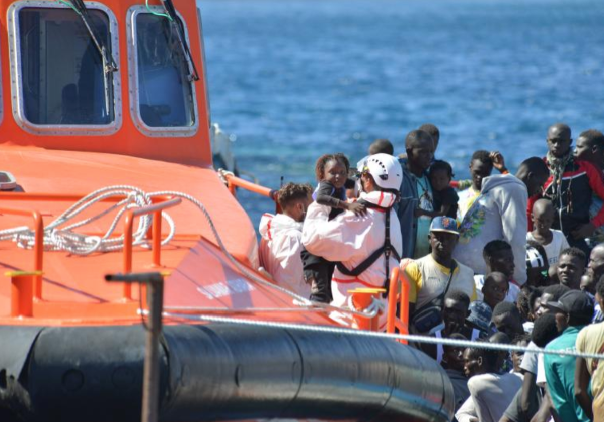 Un rescatador coge en brazos a una niña de corta edad mientras se organiza el desembarco de la Salvamar en La Restinga, El Hierro