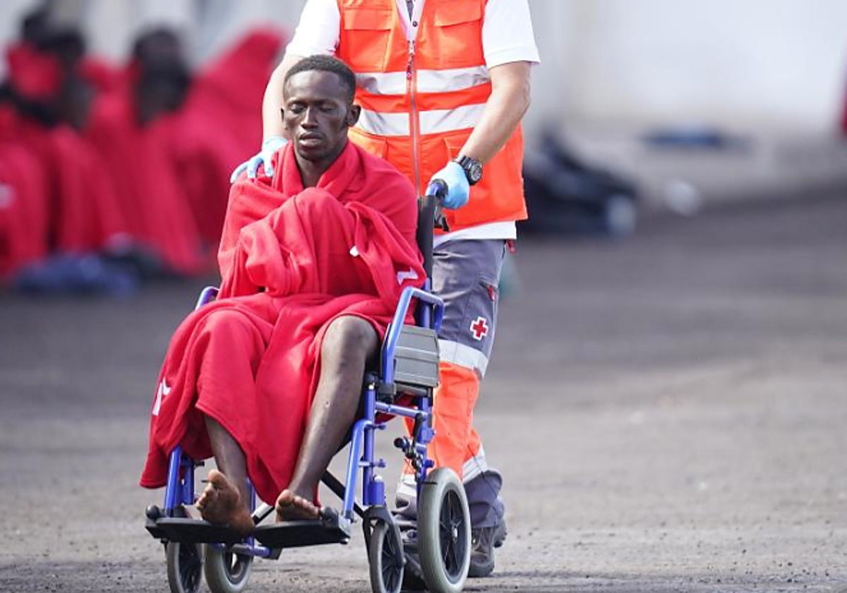 Un trabajador de Cruz Roja lleva en silla de ruedas a uno de los migrantes que llegaron a El Hierro el día 31 de octubre