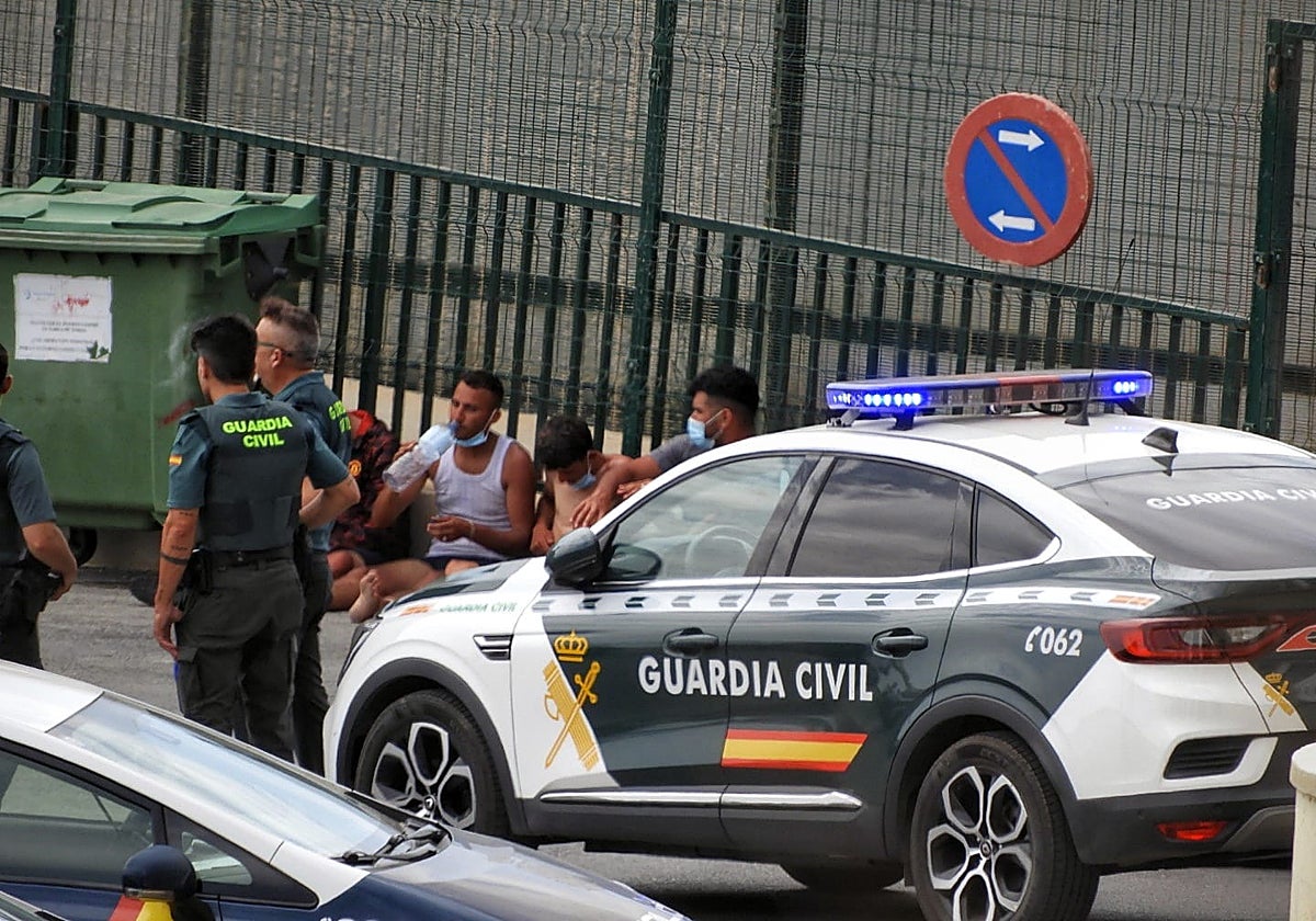 Agentes de Guardia Civil custodian a inmigrantes llegados en patera en Almería.
