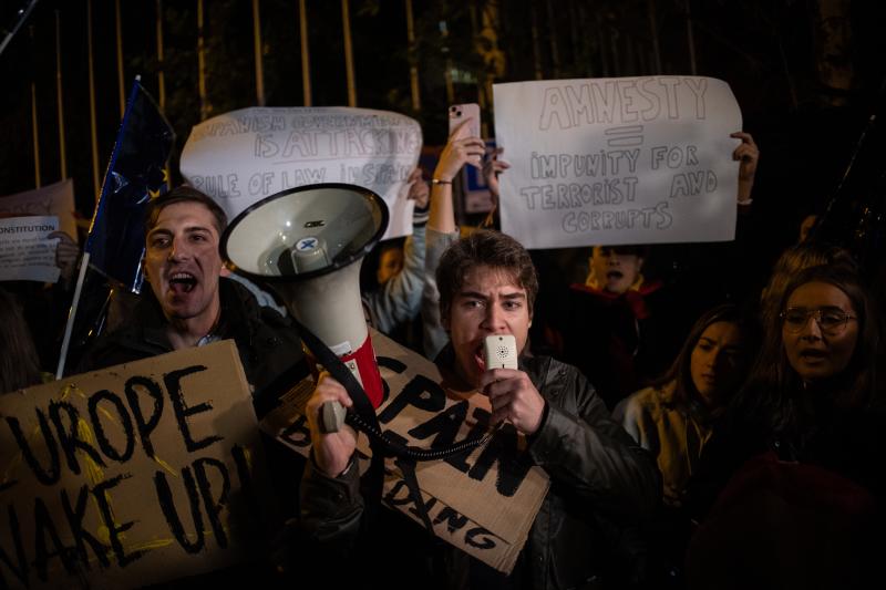 Varias personas, entre ellas dos hombres con carteles y un megáfono durante una manifestación contra la amnistía frente al Parlamento Europeo