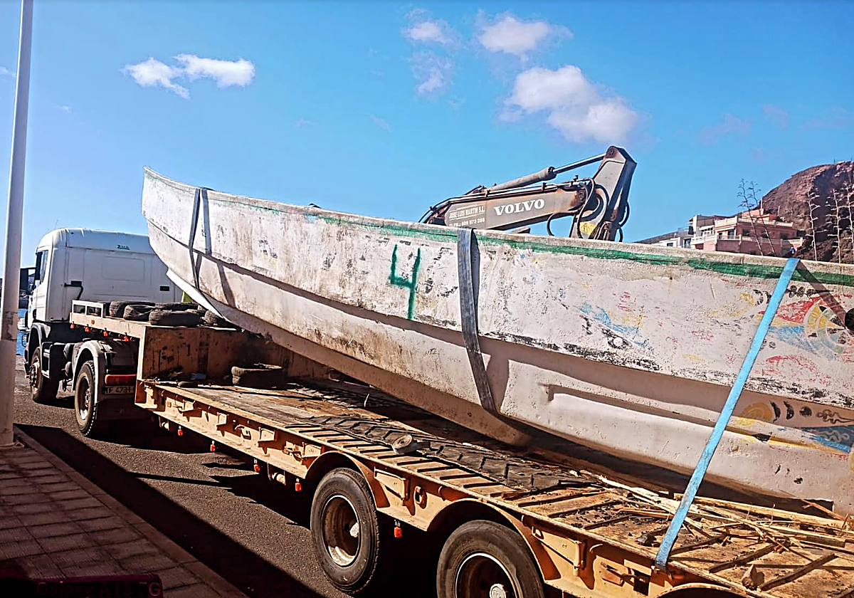 Uno de los cayucos que esperaban en el puerto es retirado para su destrucción