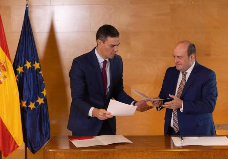 El presidente del Gobierno en funciones y candidato a la reelección, Pedro Sánchez (i), y el presidente del EBB del PNV, Andoni Ortuzar (d), firman un acuerdo para la investidura, en el Congreso de los Diputados