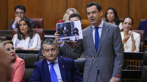 Juanma Moreno muestra la foto de Santos Cerdán y Eladio Garzón en el Parlamento andalu