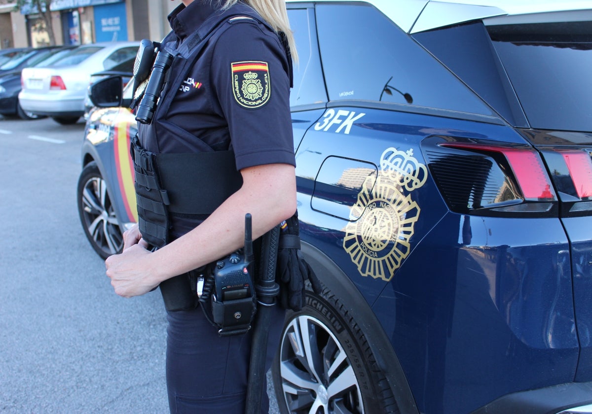 Una agente de la Policía Nacional junto a un coche patrulla en Valencia.