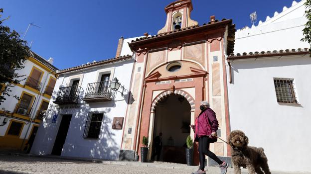 Una mujer pasa delante de la fachada de la Ermita Suites