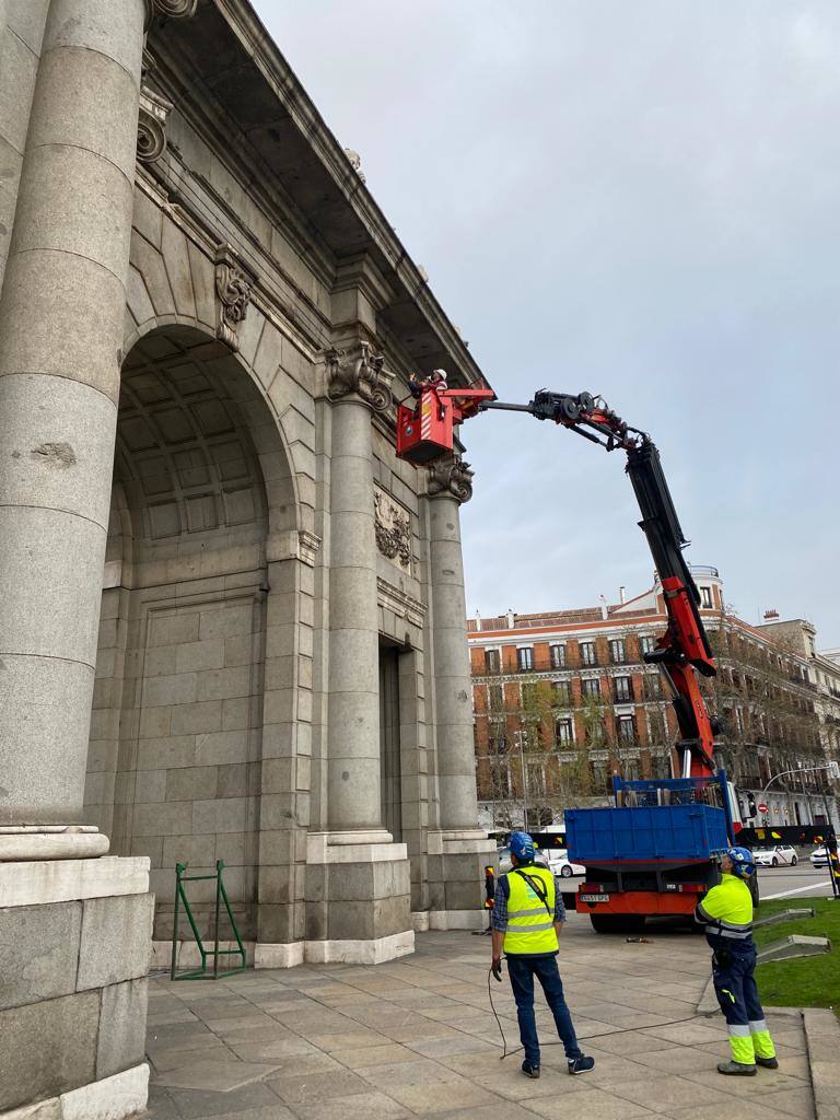 En esta imagen facilitada por el Ayuntamiento de Madrid, los técnicos se suben a una grúa para examinar la Puerta de Alcalá de cerca. Fue el primer paso, semanas antes de que se colocara la lona serigrafiada y los andamios.